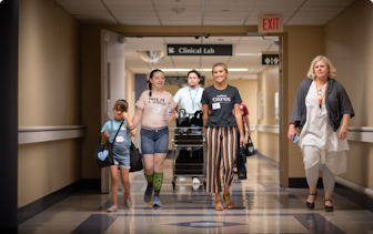 Nextiva Care's volunteer and patient walking down a hospital hallway.